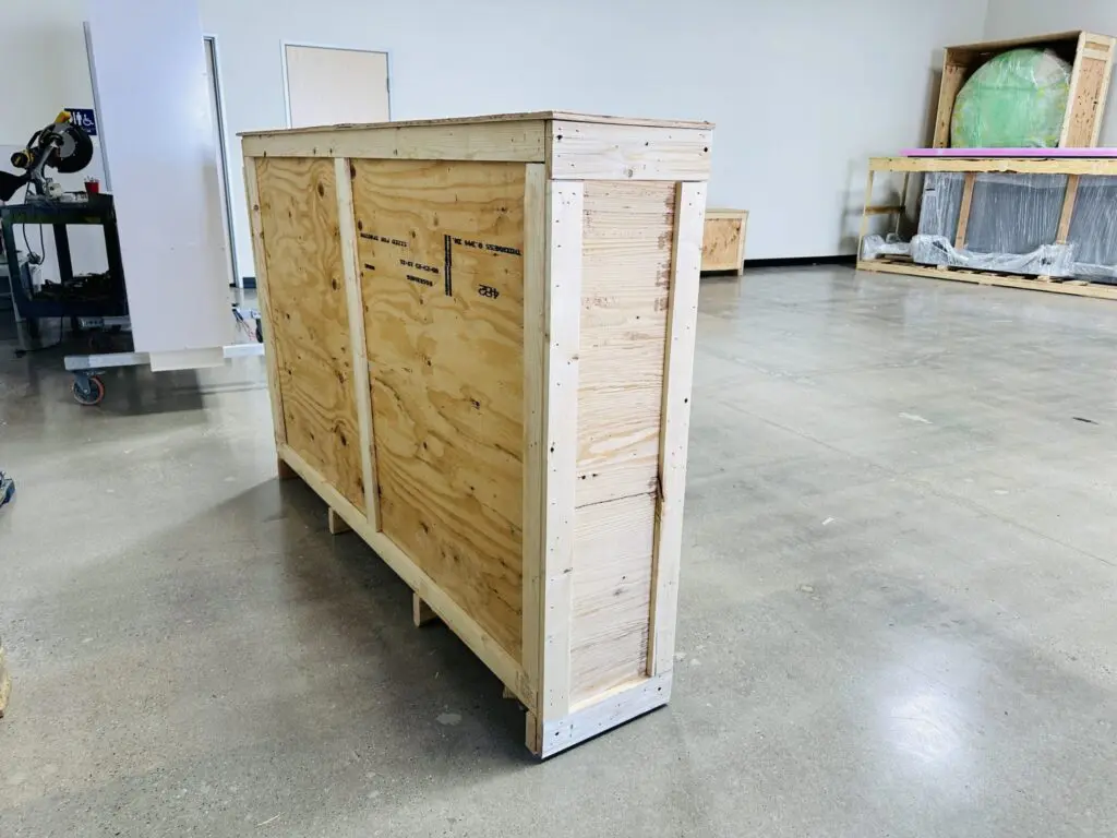 Custom wooden crate showcasing craftsmanship and tailored design for optimal protection of fragile items in a workshop setting.