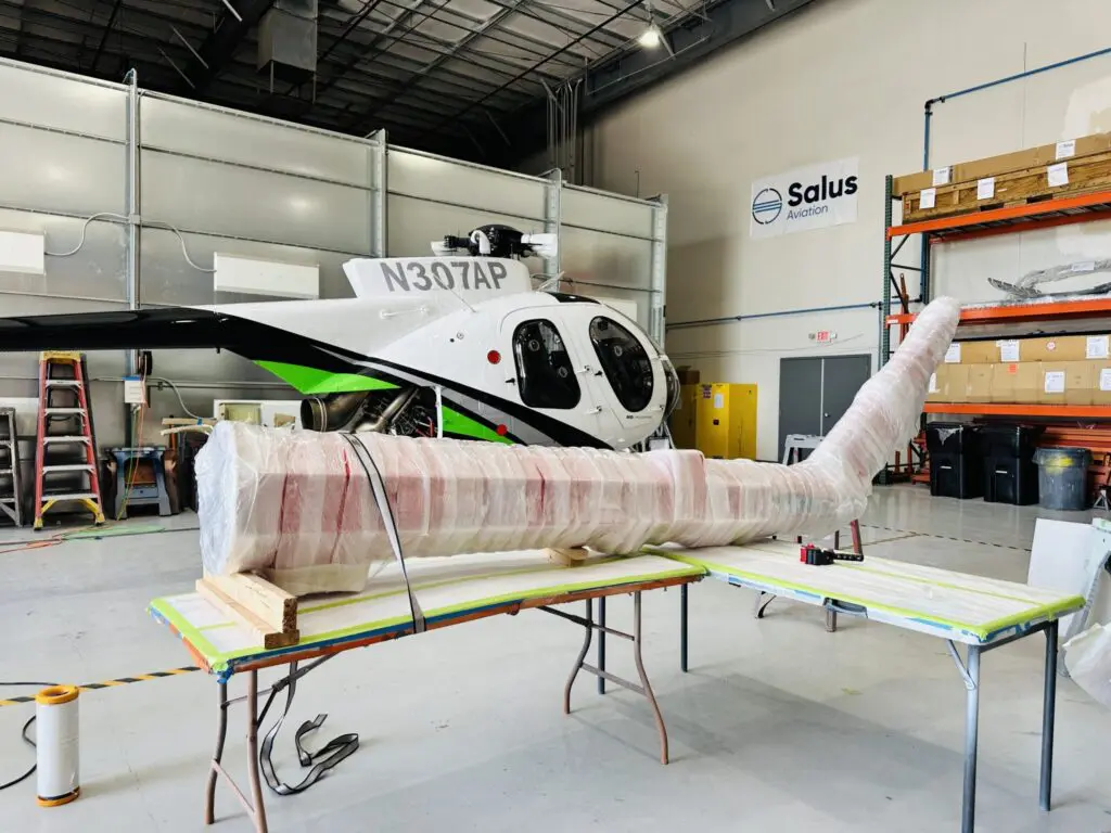 Helicopter in a hangar with a custom crated item wrapped in protective material, showcasing tailored packaging solutions for fragile cargo.
