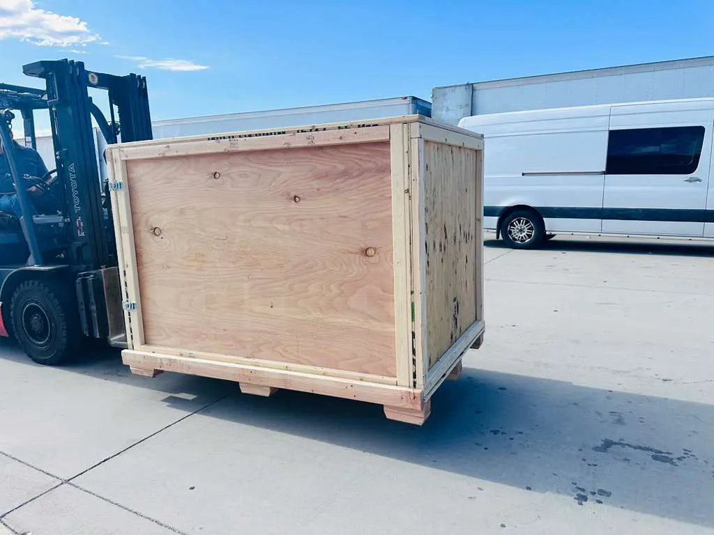 Custom wooden crate being transported by forklift, showcasing tailored design for optimal protection and stability during shipping.