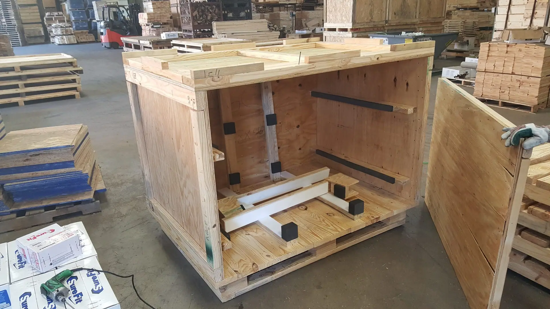 Open plywood crate with internal supports and cushioning on its base.