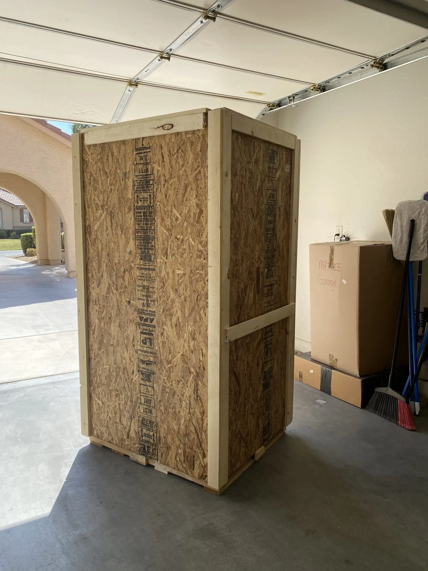 Tall closed wooden crate with framed panels inside a garage