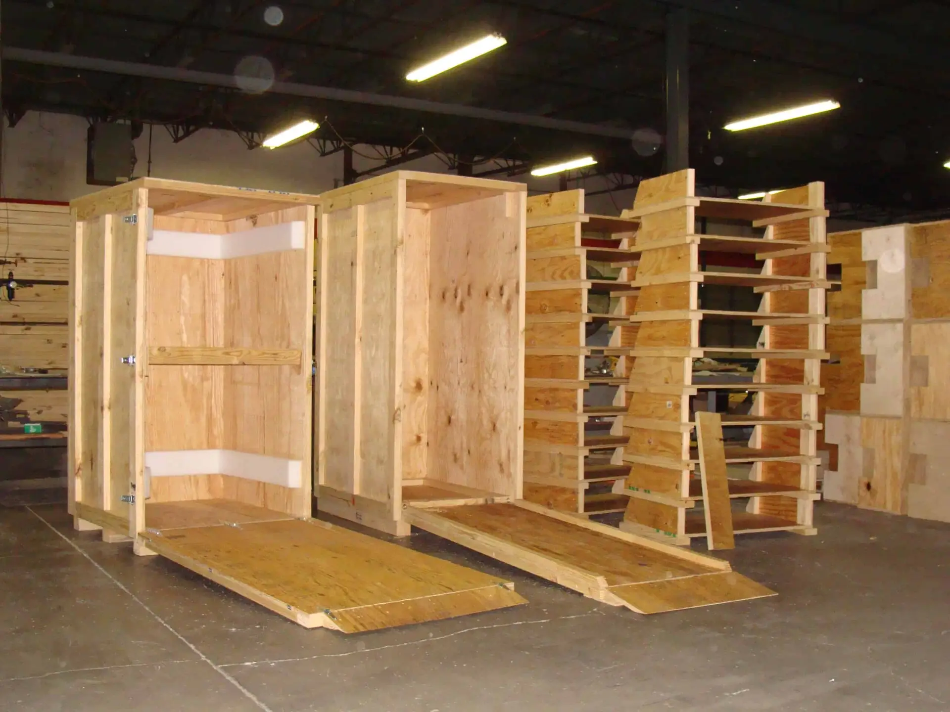 Open wood shipping enclosures with internal rails and lowered access panels.