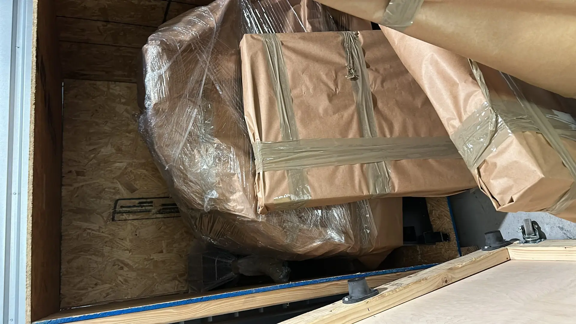 Paper-wrapped and stretch-wrapped items packed inside a wooden crate