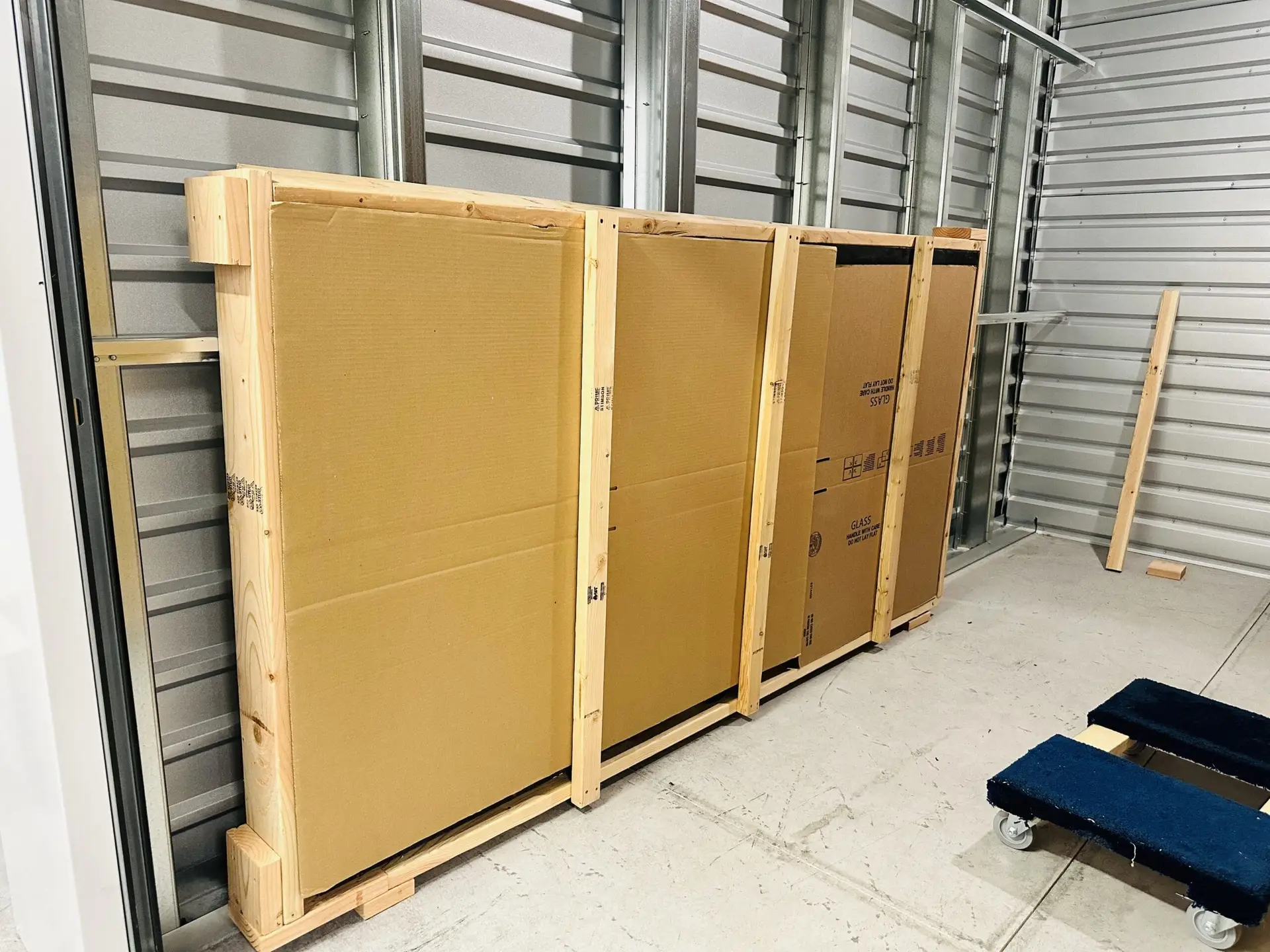 Large flat panels supported by a wooden frame inside a storage unit.