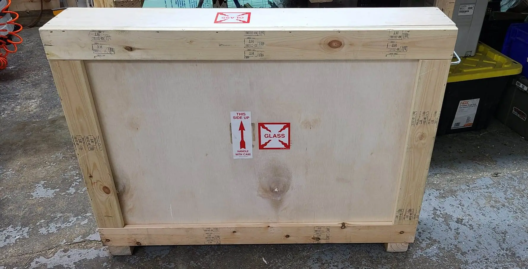 Plywood shipping crate with red handling symbols on its front panel.