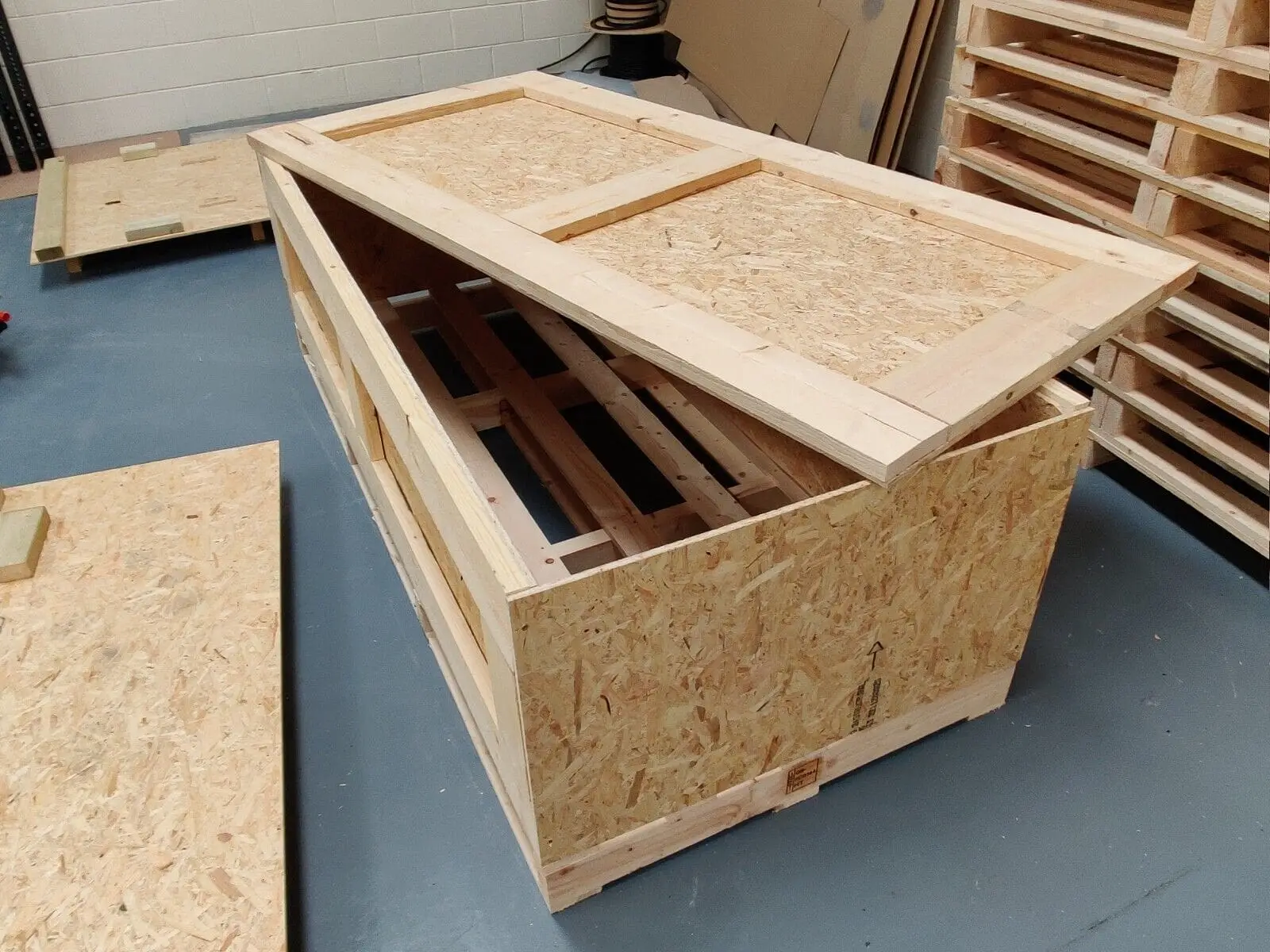 Open wood crate with its lid partly removed and timber supports inside.