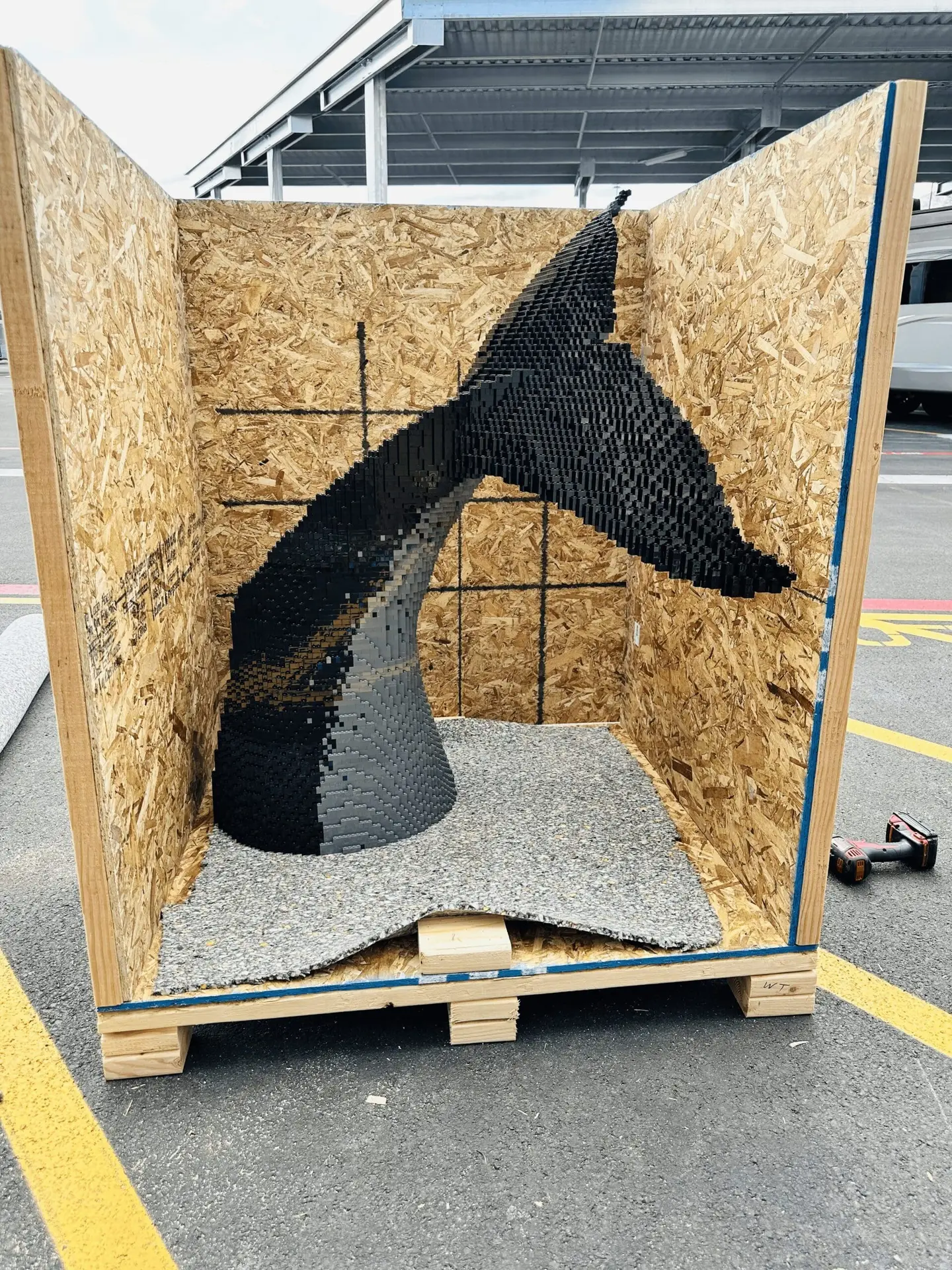 A dark horse-head sculpture inside an open wooden crate.