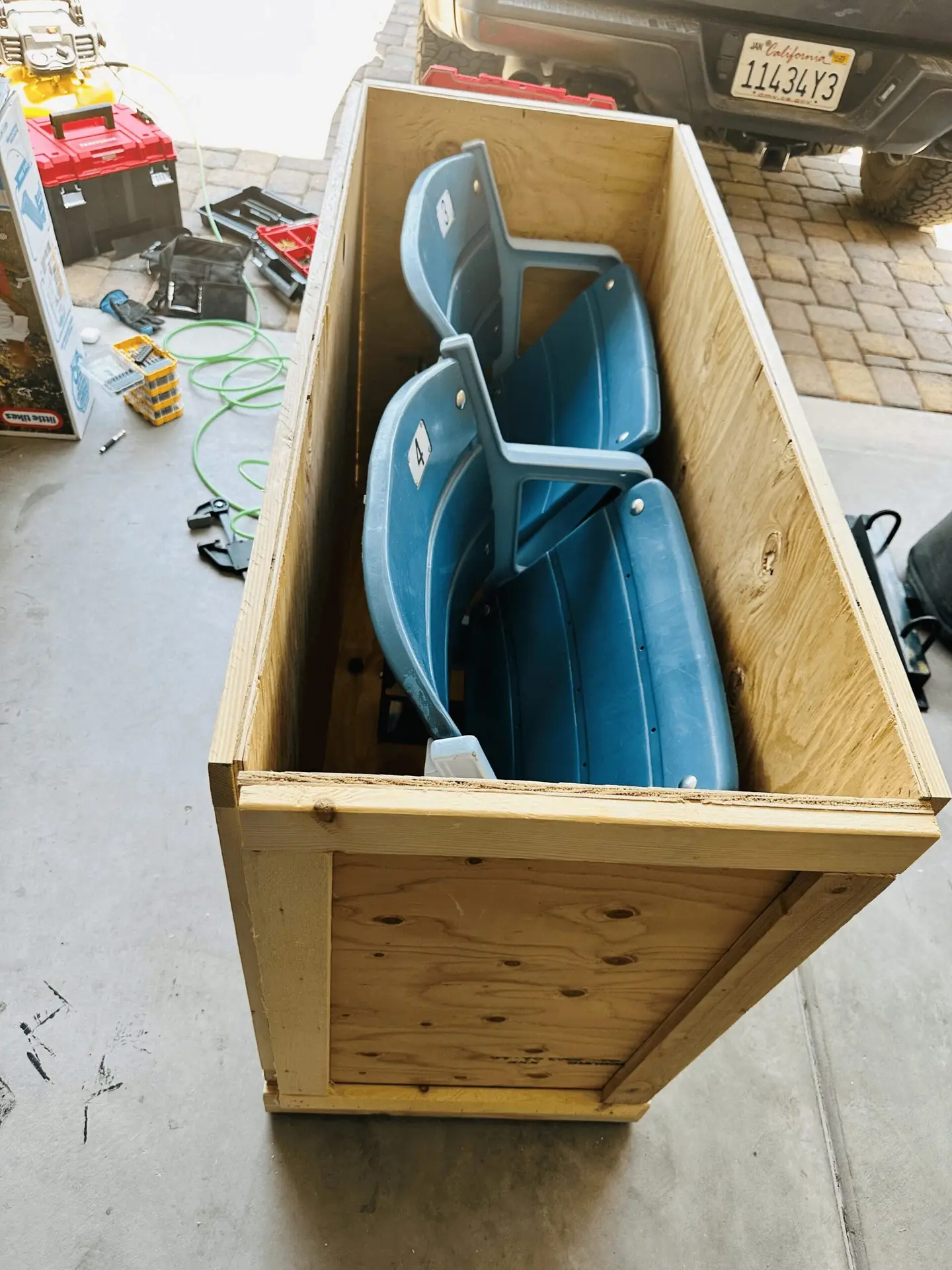 Two blue molded seats positioned inside an open wooden crate.