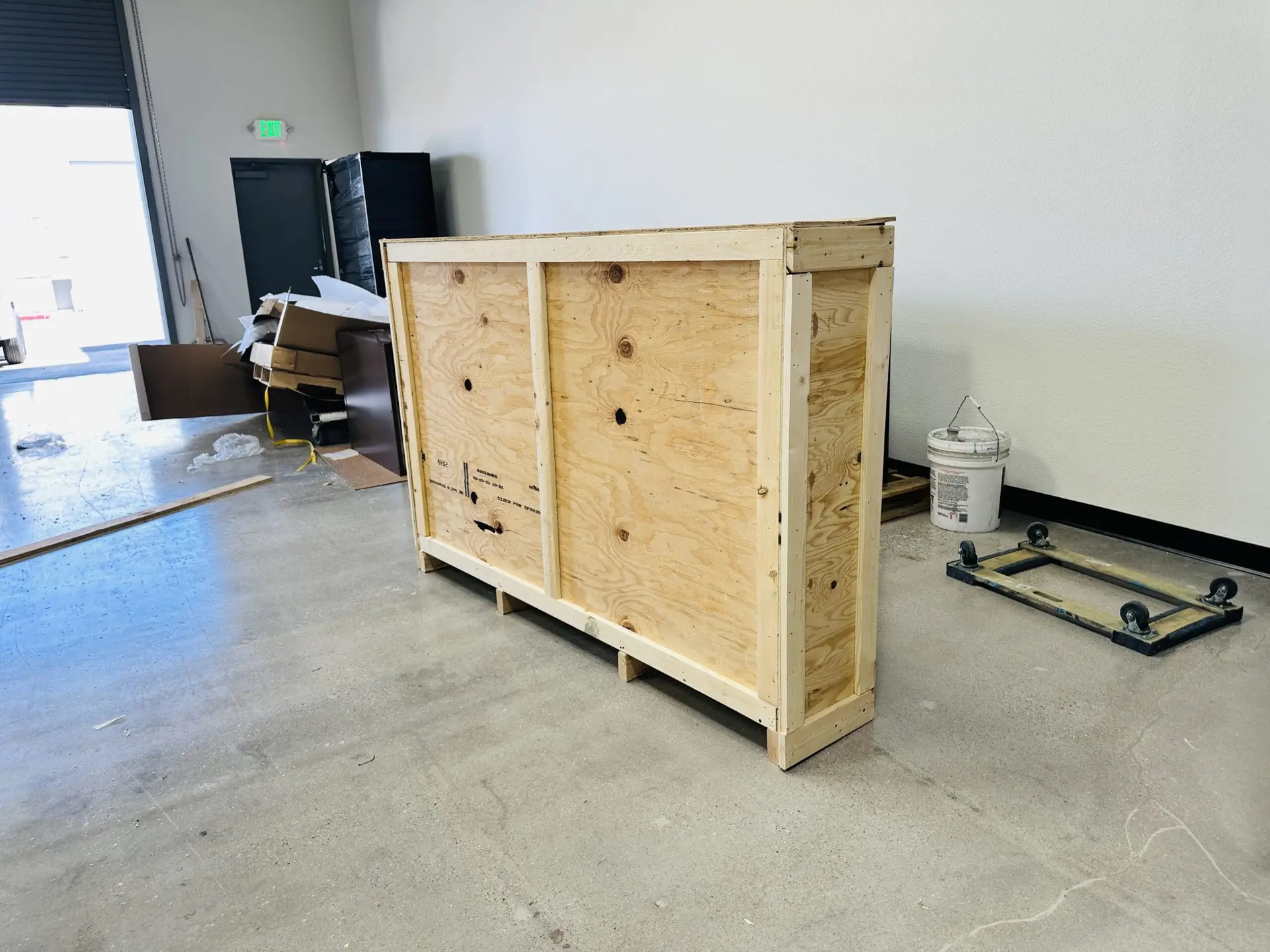 Rectangular wooden crate with vertical frame members near a workshop doorway