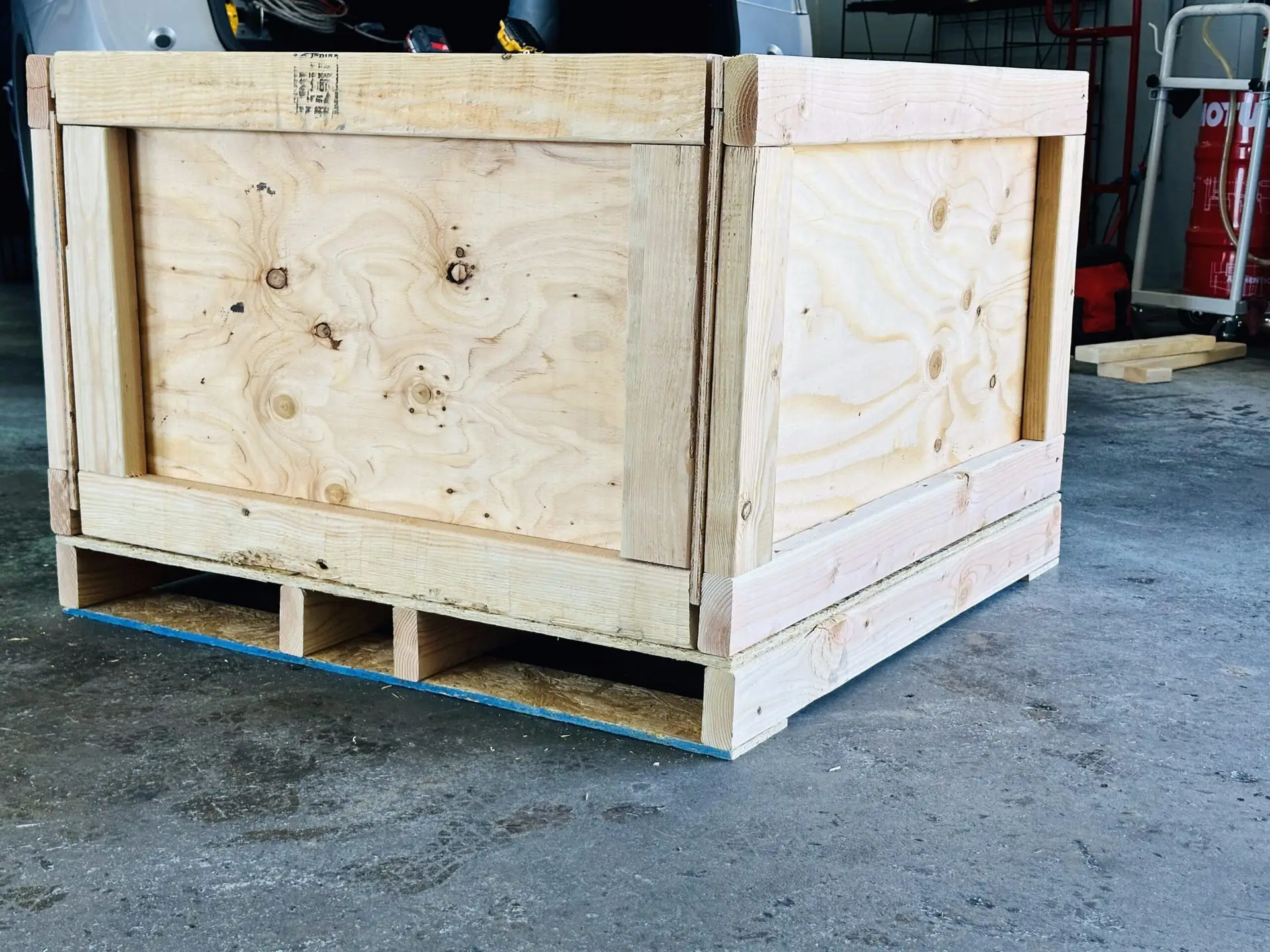 Wooden shipping crate on a pallet base at a workshop entrance.