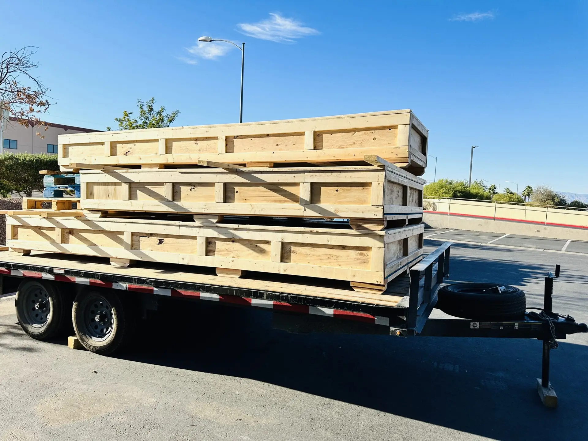 Long wooden shipping crates stacked on a flatbed trailer outdoors.