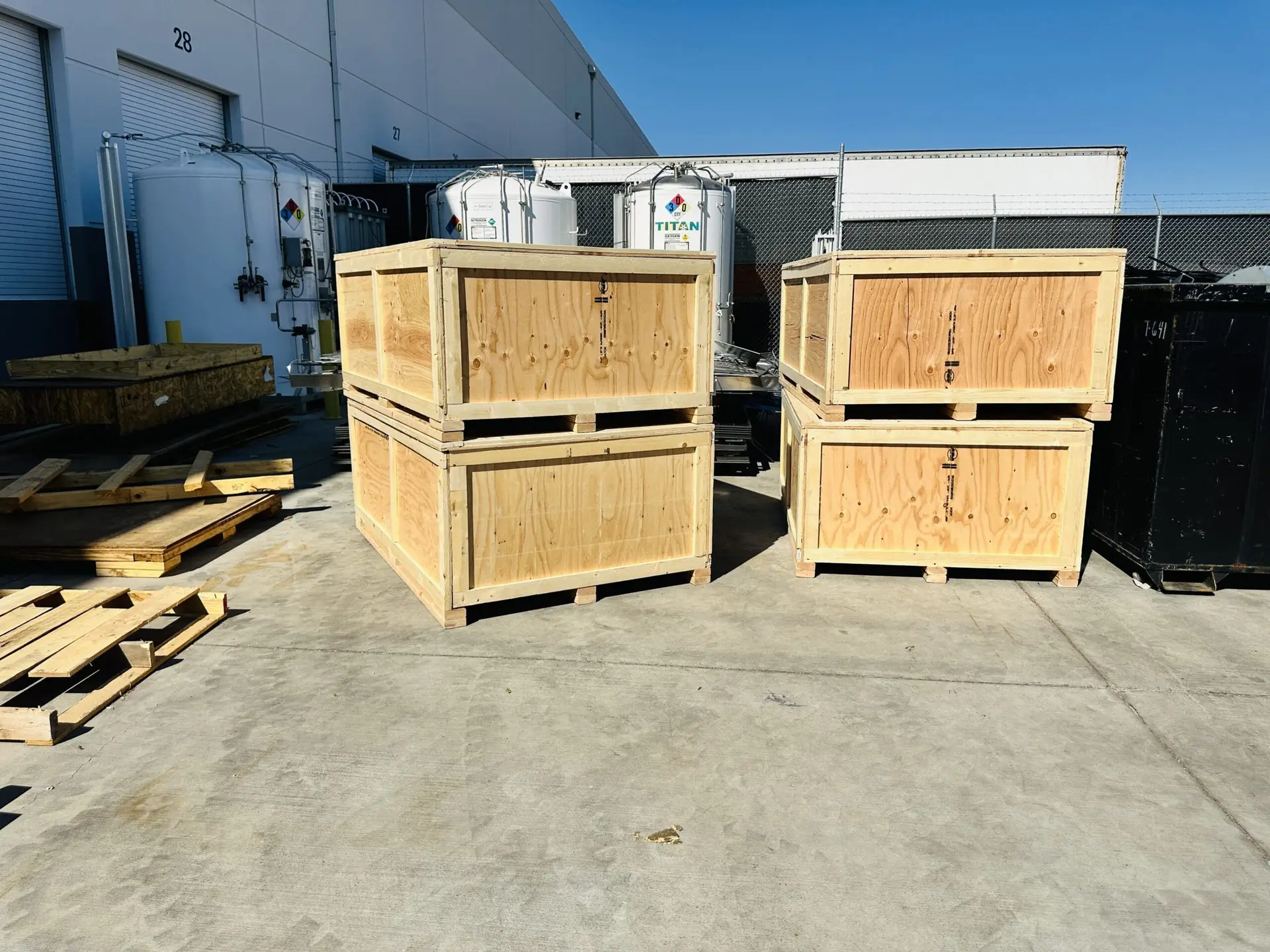 Wooden shipping crates stacked in pairs outside a warehouse.