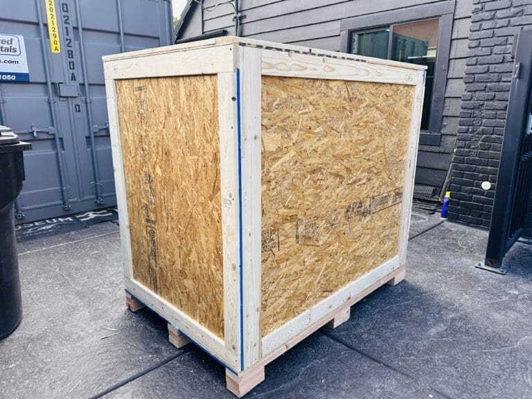 Custom wooden crate on pallet in storage area, showcasing durable materials for secure transport and tailored crating solutions by Crates of Las Vegas.