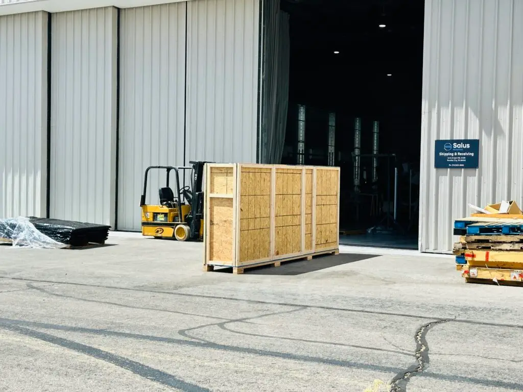 Custom wooden crate and forklift in warehouse illustrating freight shipping solutions.