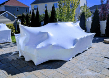 White heat shrink wrap covering outdoor furniture on a patio, illustrating protective packaging for items during storage or transit.